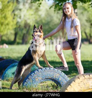 Ragazza adolescente in camicia bianca con il suo cane seduto sul sentiero nel Parco Foto Stock