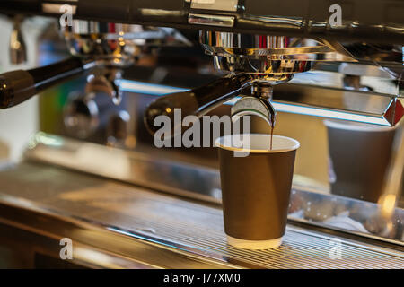 Close-up espresso fresco si versa nel bicchiere di carta, Italiano macchina espresso. Cultura del caffè e professional caffè, servizio, concetti di ristorazione Foto Stock