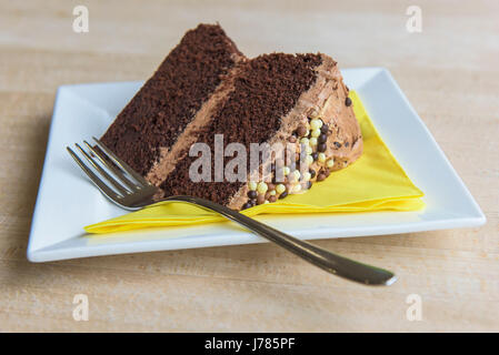 Una vista ingrandita di una fetta di torta al cioccolato; piastra; forcella; salvietta; igienico; cibo; trattare; dolce; burro glassa; Topping; indulgenza; lusso; calorie Foto Stock