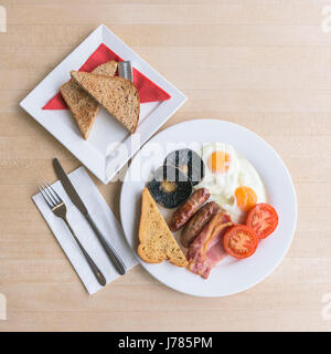 Una vista in pianta di una prima colazione inglese completa; cibo; pasto mattutino; fry up; calorie; toast, uova, bacon, salsicce, pane fritto; campo di funghi;