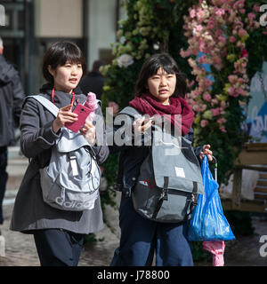 Londra, Inghilterra - Marzo 12, 2017 Due turisti giapponesi con i telefoni rosa e zaini vai sul carrello Foto Stock