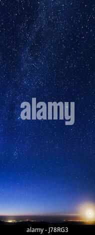 Luna crescente su montagne e luci della città con la parte settentrionale della via lattea Foto Stock