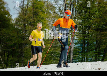 Due corridori uomini in esecuzione sentiero innevato con pali trekking in gara chilometro verticale Foto Stock