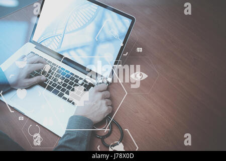 Vista superiore della smart medico lavora con lo stetoscopio e laptop e tablet digitale computer in legno scuro, scrivania con schema Vr Foto Stock