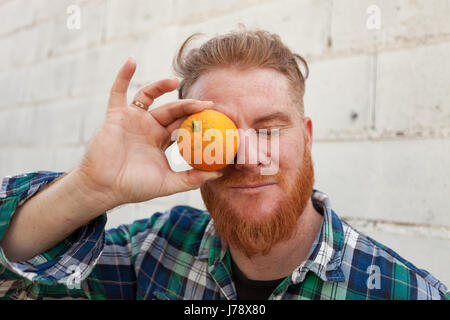 Dai capelli rossi uomo con un arancione prima il suo occhio Foto Stock