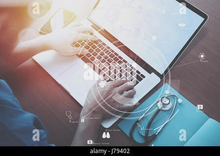 Vista superiore della smart medico lavora con lo stetoscopio e laptop e tablet digitale computer in legno scuro, scrivania con schema Vr Foto Stock