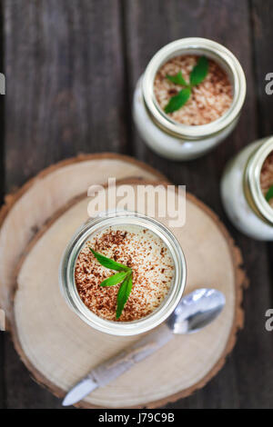 Il tiramisù. Tre porzioni su un tavolo di legno con la menta Foto Stock