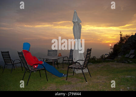 La mattina presto in Stiria Alpi calcaree. Una persona che sta guardando il Rising Sun. Parco Nazionale Gesäuse, Steiermark, Austria. Foto Stock