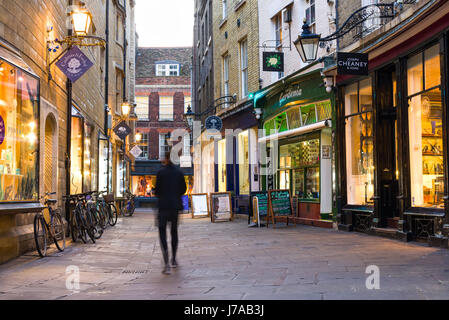 Rose Crescent negozi accesa fino al tramonto con la persona che cammina lungo la pavimentazione di pietra, Cambridge, Regno Unito Foto Stock