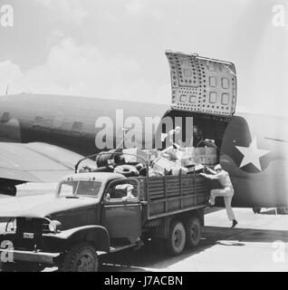 Lo scarico del carico da un U.S. L'esercito dell'aria di comando di trasporto aereo cargo, circa 1943. Foto Stock