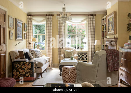 Uno stile tradizionale inglese soggiorno con stile Howard poltrona, lacca petto da Colefax & fowler e lampadari di antiquariato. Foto Stock