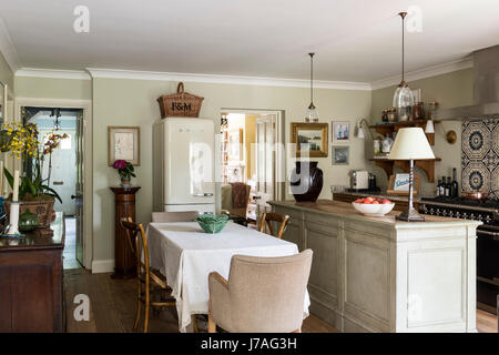Elegante e tradizionale cucina feeling con antico tavolo da pranzo e sedie, Smeg frigo e macellai isola. Il pendente luci sono da Hector Finch Foto Stock