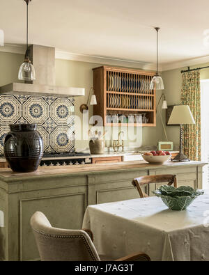 Vecchio Minton piastrelle al di sopra della gamma fornello in elegante e accogliente cucina con cerata unità di pino e macellai isola. Il pendente luci sono da Hector Finch Foto Stock