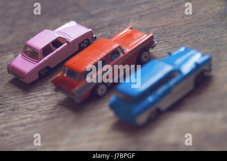 Orizzontale basso angolo di visione closeup di tre vintage colorate automobili giocattolo in legno marrone piano fuoco selettivo copyspace Foto Stock
