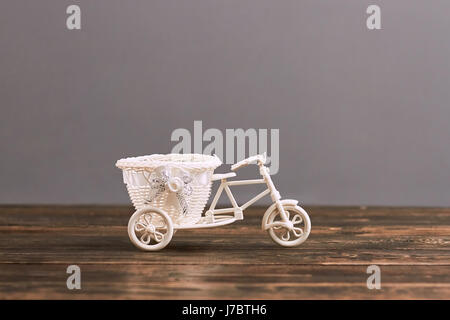 Triciclo Piccolo cesto fiorito. Giocattolo di plastica su una superficie di legno. Vintage Toys in vendita. Foto Stock