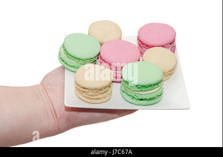 Donna mano che tiene una piastra bianca con colorato dolce amaretti, francese tradizionale, crema, vicino, sfondo bianco Foto Stock
