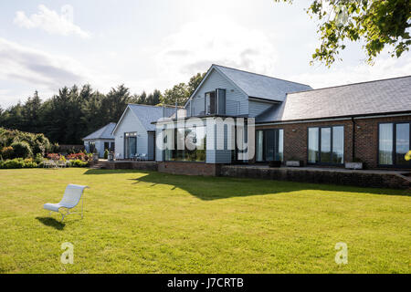 Weatherboard esterna di rinnovato Sussex bungalow, dipinto in grigio per la miscela al paesaggio naturale Foto Stock