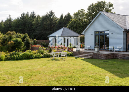 Weatherboard esterna di rinnovato Sussex bungalow, dipinto in grigio per la miscela al paesaggio naturale Foto Stock