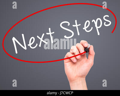 Man mano che scrive i passi successivi con pennarello nero su schermo visivo. Isolato su grigio. Business, tecnologia internet concetto. Immagine di stock Foto Stock