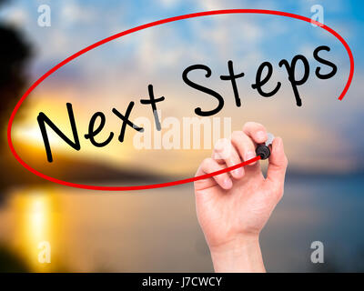 Man mano che scrive i passi successivi con pennarello nero su schermo visivo. Isolato sulla natura. Business, tecnologia internet concetto. Immagine di stock Foto Stock