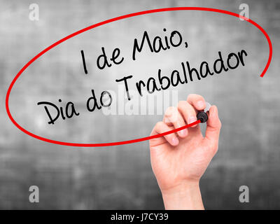 Man mano che scrive 1 de Maio, dia do Trabalhador (in portoghese: 1 maggio, Giornata del Lavoro) con pennarello nero su schermo visivo. Isolato su grigio. Business, TEC Foto Stock