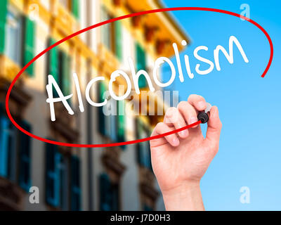 Man mano che scrive alcolismo con pennarello nero su schermo visivo. Isolato su sfondo. Business, tecnologia internet concetto. Stock Photo Foto Stock