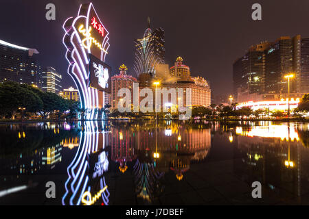 Macao, Cina - 23 Aprile 2017: le luci di un famoso casinò operatore Wynn riflettere sull'acqua con il Lisboa Casinò torre in background. Macao rece Foto Stock