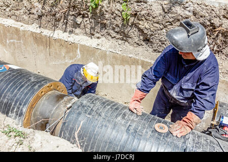 Lavoratore è la pulizia di cordone di saldatura sulla tubazione con una rettificatrice. Preparazione per la saldatura Foto Stock