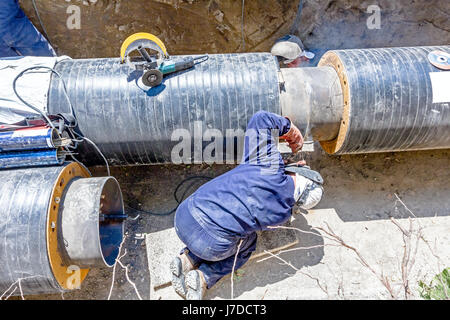 Il team di saldatori è in trincea lavorando duro per installare un nuovo gasdotto. Saldatura ad arco tubi Foto Stock