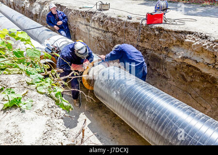 Il team di saldatori è in trincea lavorando duro per installare un nuovo gasdotto. Saldatura ad arco tubi Foto Stock