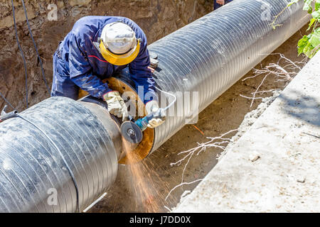 Lavoratore è la pulizia di cordone di saldatura sulla tubazione con una rettificatrice. Preparazione per la saldatura Foto Stock