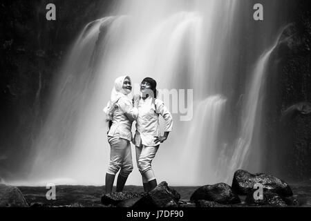 Le ragazze in posa a cascata surreale per il bianco e nero foto ritratto con ethereal lisce come la seta cascata in background. Drammatica esposizione lunga Foto Stock