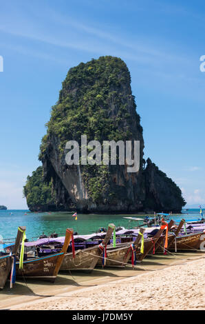 Lunga coda di barche e roccia carsica formazione a Phra Nang Beach, Railay, Krabi, Thailandia Foto Stock