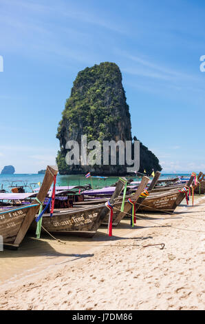 Lunga coda di barche e roccia carsica formazione a Phra Nang Beach, Railay, Krabi, Thailandia Foto Stock