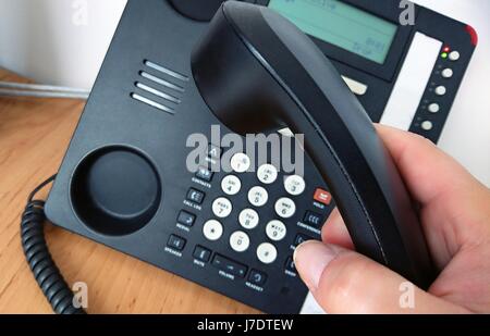 Close-up di picking cornetta del telefono per effettuare una chiamata. Foto Stock