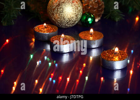 Alcuni accendendo candele su vetro surfase con la riflessione sullo sfondo con giocattoli di Natale Foto Stock