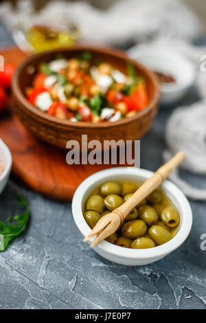 La molla insalata di verdure con foglie di rucola, pomodori ciliegini, ceci, olive e formaggio feta. Ciotola di Buddha. Profondità di campo. Foto Stock