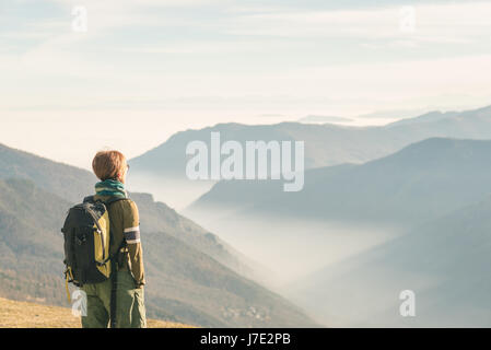 Escursionista femmina con zaino guardando la maestosa vista sulle Alpi italiane. La nebbia e la nebbia nella valle sottostante, nevato picco di montagna nel backgro Foto Stock