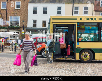 I passeggeri scendono dalla dipendenza bus nella Piazza del Mercato di Thirsk, North Yorkshire England Regno Unito Foto Stock