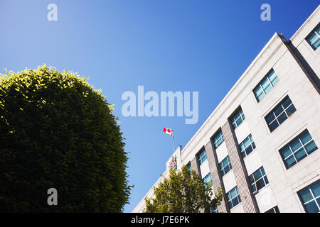 Bandiera canadese soffiando nel vento in cima all'edificio. Victoria BC Canada Foto Stock