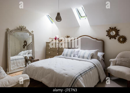 Ornati specchio francese in camera per ospiti con letto da piuma & Nero. Le pareti sono dipinte di scrematura di pietra da Farrow & Ball Foto Stock