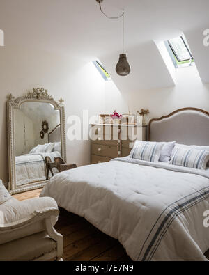 Ornati specchio francese in camera per ospiti con letto da piuma & Nero. Le pareti sono dipinte di scrematura di pietra da Farrow & Ball Foto Stock