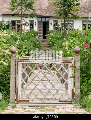 Gated passerella e giardino con tetto di paglia del xvii secolo famhouse costruito nel XII secolo earthmound per impedire allagamento Foto Stock