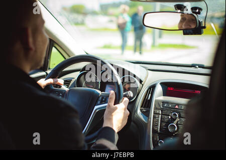Giovane uomo barbuto alla guida di una vettura, cabina interna giostre, guardando road, guida, trattenendo il volante. Foto Stock