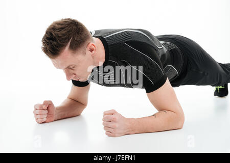 Ritratto di un giovane concentrato uomo fitness facendo esercizio tavoloni isolate su sfondo bianco Foto Stock