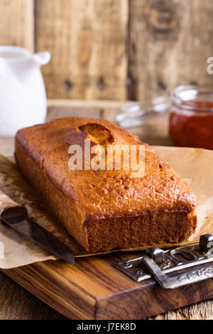 In casa ciambellone sulla carta da forno servita con marmellata di frutta pronto a mangiare sulla tavola in legno rustico, delizioso brunch o tea time Foto Stock