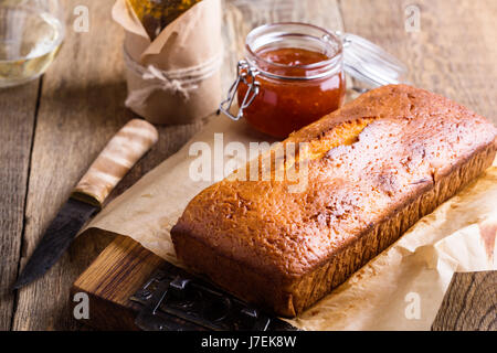 In casa ciambellone sulla carta da forno servita con marmellata di frutta pronto a mangiare sulla tavola in legno rustico, delizioso brunch o tea time Foto Stock