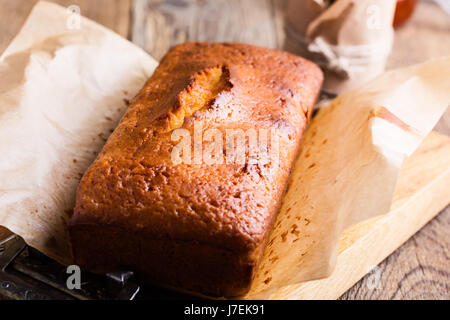 In casa ciambellone sulla carta da forno servita con marmellata di frutta pronto a mangiare sulla tavola in legno rustico, delizioso brunch o tea time Foto Stock