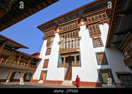 Monaco camminando a paro Rinpung Dzong, monastero buddista e fortezza su una collina vicino il Paro Chu fiume. Stile bhutanese edificio decorato con scolpito Foto Stock