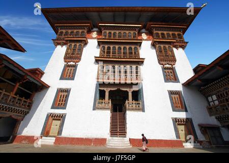 La donna nel tradizionale abito bhutanesi camminando a paro Rinpung Dzong, monastero buddista e fortezza su una collina vicino il Paro Chu fiume. Lo stile del Bhutan Foto Stock